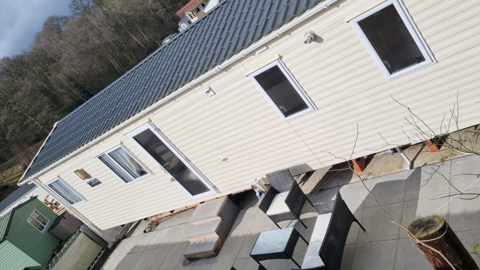 Angled view looking down onto the side of a static caravan with outside table and chairs