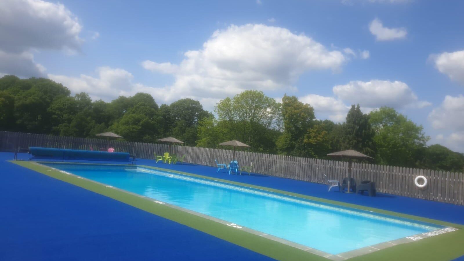 The outdoor heated swimming pool at bank farm on a summers day with a blue sky above and white fluffy clouds.