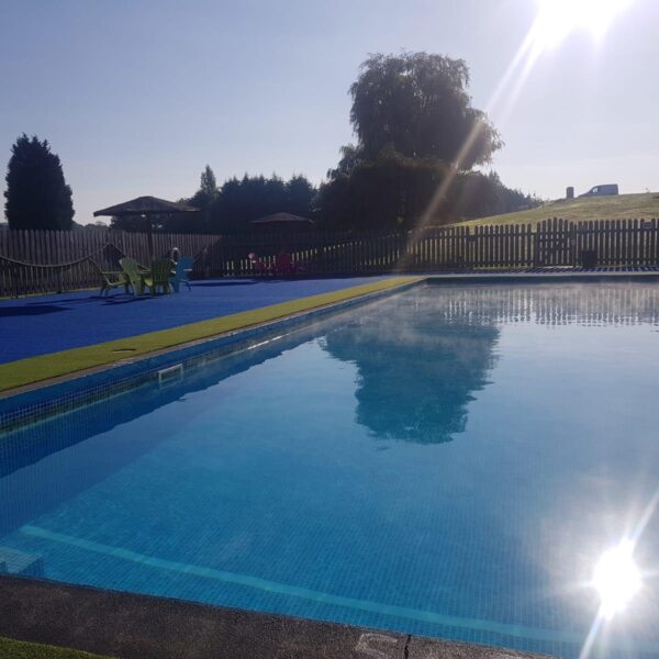 The evening sun shines down onto the outdoor heated swimming pool at Bank Farm.